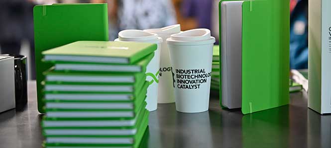 IBIC branded notebooks and coffee cups on display at a conference