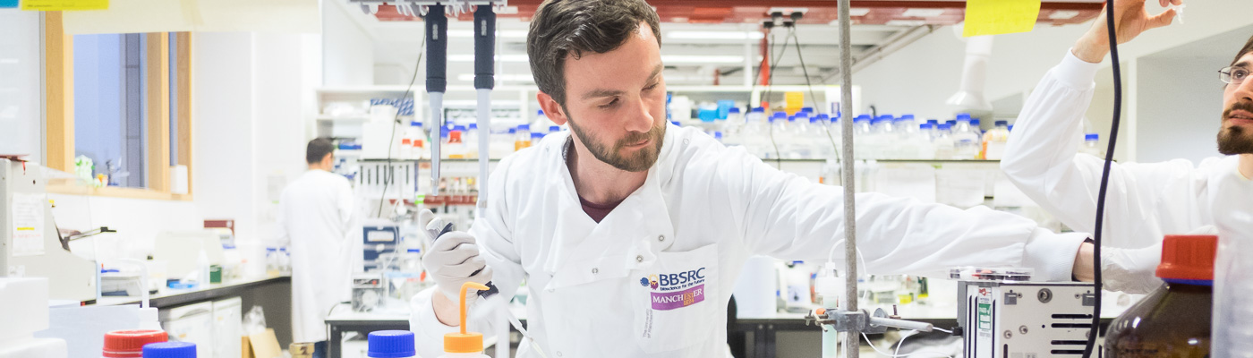 A male scientist in a white lab coat works in a lab.