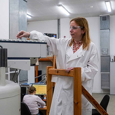 A scientist loads a sample into an NMR machine.