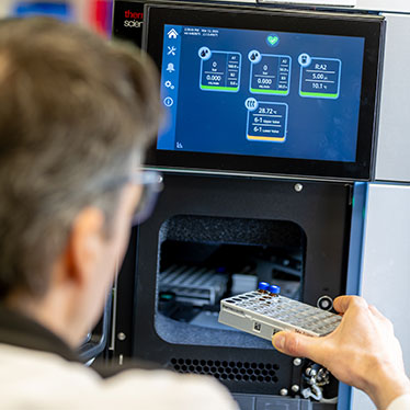A scientist loads samples into a mass spectrometer.