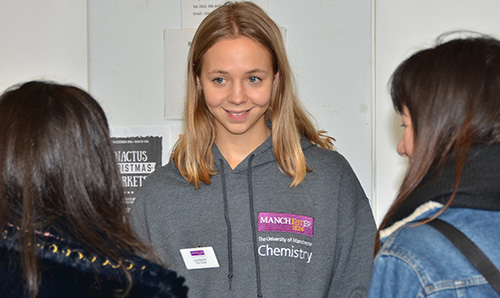 Female chemistry students talking to students at an event