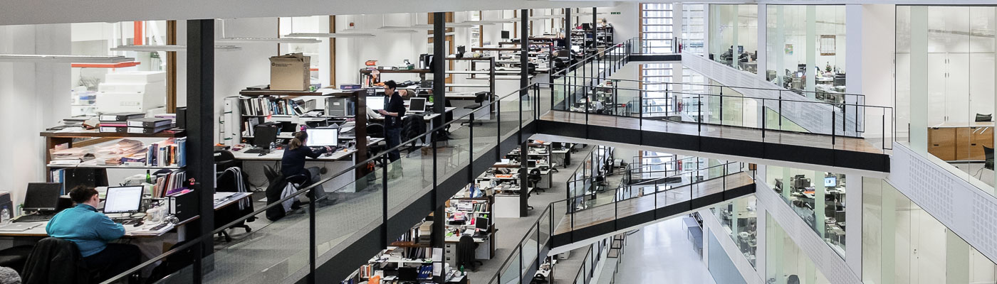 A large atrium of a building with elevated walkways and workspaces along the sides.